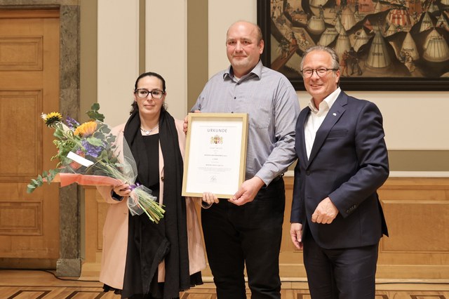 Der Preisträger präsentieren gemeinsam mit dem Bürgermeister seine Urkunde.